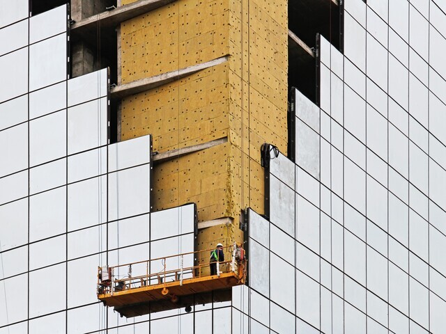 High-rise building construction showing the installation of Class-A fireproof Rockwool insulation behind a glass and metal curtain wall facade