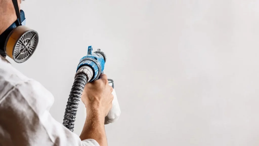 Professional worker applying aerogel thermal insulation coating using a high-pressure spray gun